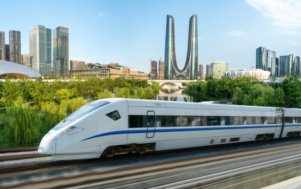 A Chinese high-speed train passing a modern city skyline