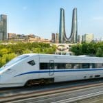 A Chinese high-speed train passing a modern city skyline
