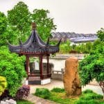 A traditional garden pavilion beside a canal in Suzhou, surrounded by greenery