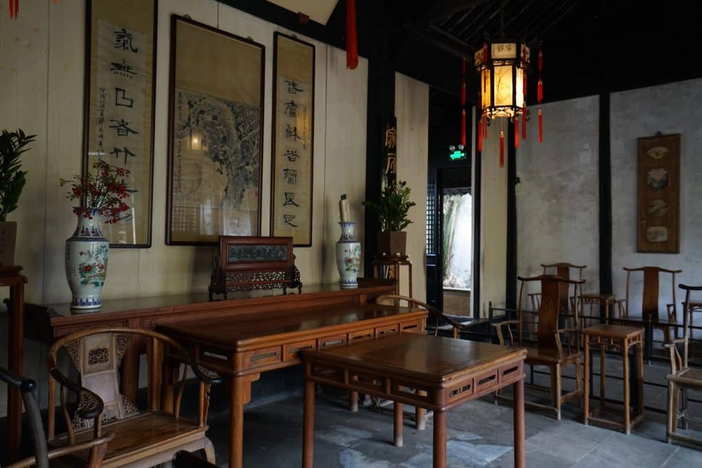 Interior of Shen Hall, a preserved Qing-dynasty merchant residence in Zhouzhuang near Suzhou, with hardwood furniture, calligraphy scrolls, and a red-tasseled lantern
