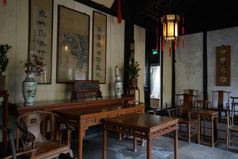Interior of Shen Hall, a preserved Qing-dynasty merchant residence in Zhouzhuang near Suzhou, with hardwood furniture, calligraphy scrolls, and a red-tasseled lantern