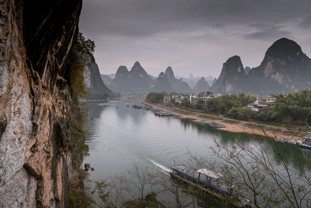 The Li River running past a village below karst peaks at Yangshuo