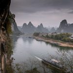 The Li River running past a village below karst peaks at Yangshuo