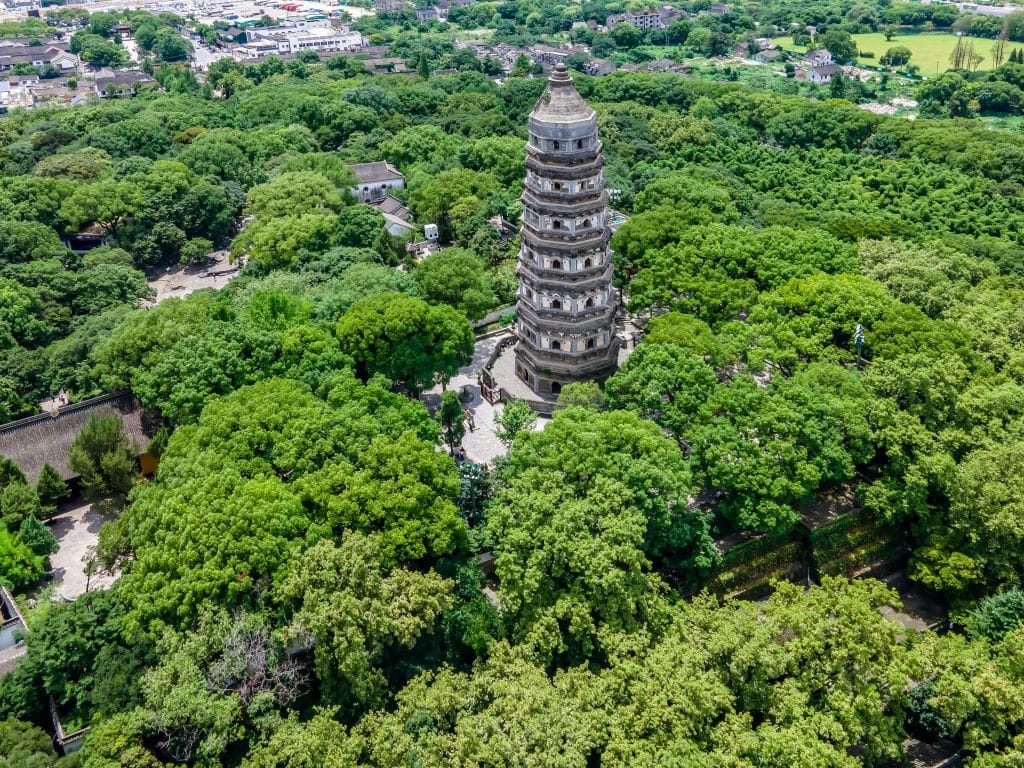 Aerial view of the leaning Tiger Hill Pagoda surrounded by forest in Suzhou