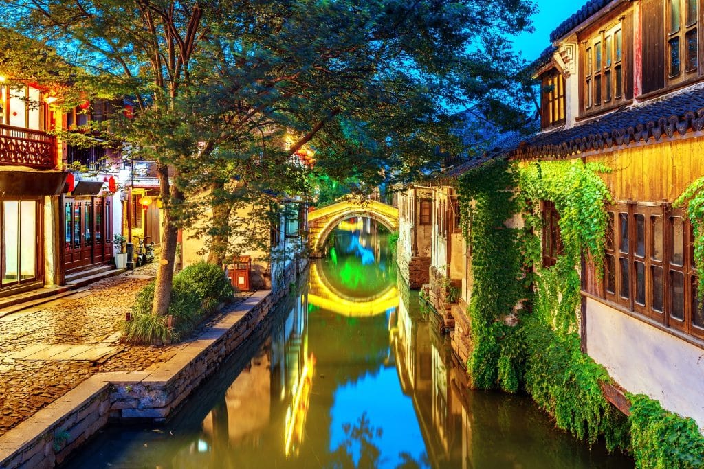 Stone arch bridge reflected in a canal between traditional whitewashed houses in Zhouzhuang water town near Suzhou