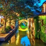 Stone arch bridge reflected in a canal between traditional whitewashed houses in Zhouzhuang water town near Suzhou