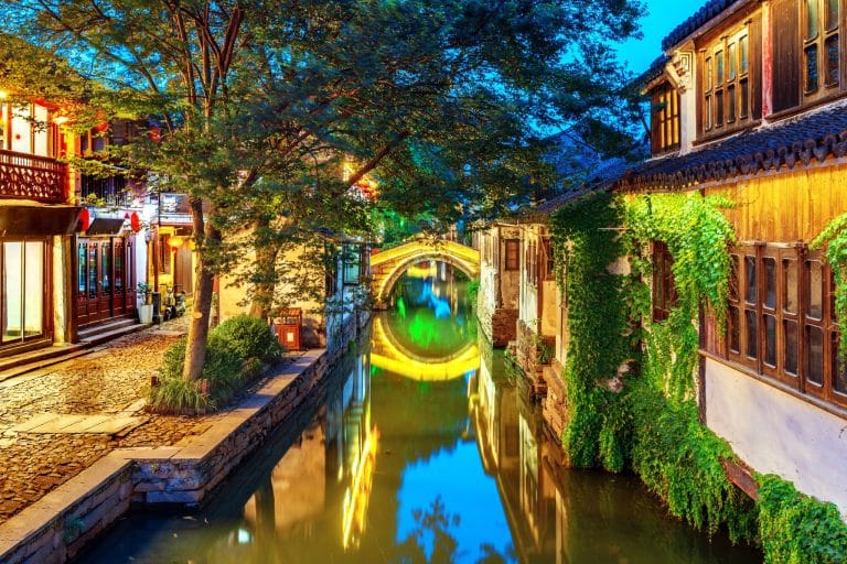 Stone arch bridge reflected in a canal between traditional whitewashed houses in Zhouzhuang water town near Suzhou