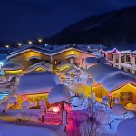 China Snow Town at night, wooden houses with thick rounded caps of snow on their roofs, lit by red lanterns and coloured lights