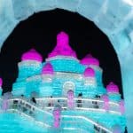 Lit ice castle behind an ice fence at night, Harbin Ice and Snow Festival, January 2022