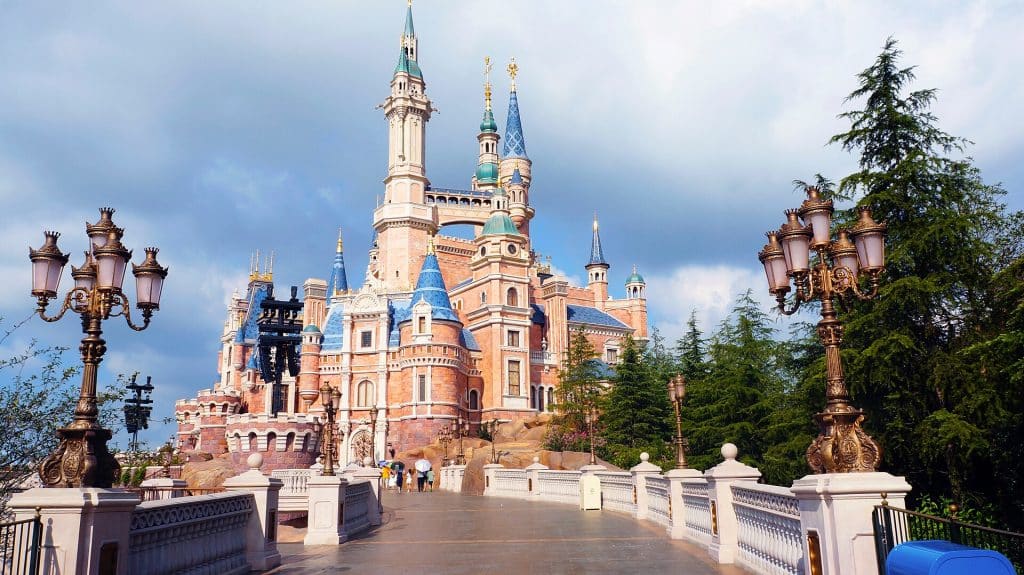 Enchanted Storybook Castle at Shanghai Disneyland seen along a lamp-lined promenade under a blue sky
